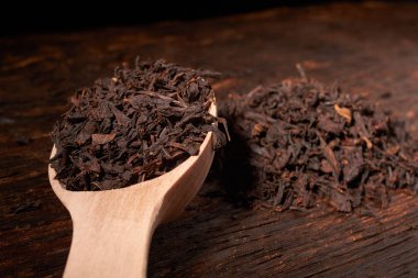 Tahta kaşık çay siyah yapraklarda siyah koyu ahşap masa