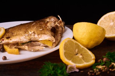 limon dilimleri, baharat ve fırın tepsisine, taze biberiye ile lezzetli kavrulmuş sazan balık yukarıdan görüntülemek
