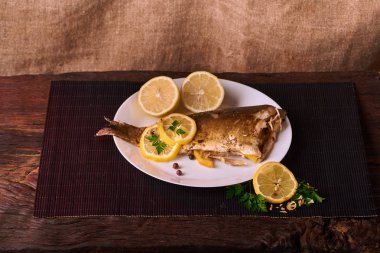 Kavrulmuş sazan ile ahşap masa tabakta dorado balık maydanoz, chives ve limon ile