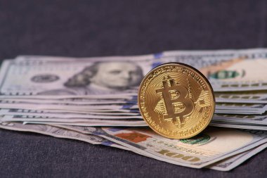 Güzel gri bir arka plan üzerinde faturaları 100 dolar ve altın sikke bitcoin düzenlenmiş. Bitcoin cryptocurrency. Anonim