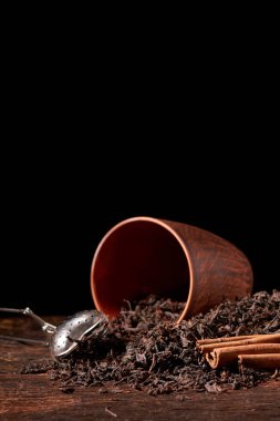 Kuru çay yaprakları ve tarçın darck ahşap arka plan üzerinde sopa ile çay süzgeci resmini