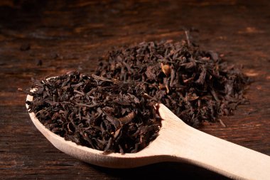 Tahta kaşık çay siyah yapraklarda siyah koyu ahşap masa