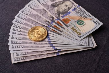 Güzel gri bir arka plan üzerinde faturaları 100 dolar ve altın sikke bitcoin düzenlenmiş. Bitcoin cryptocurrency. Anonim