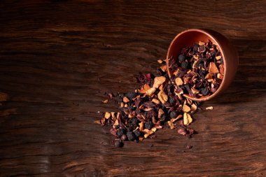 bir ahşap masa ve siyah arka plan üzerinde bir kil kase meyve çayı.