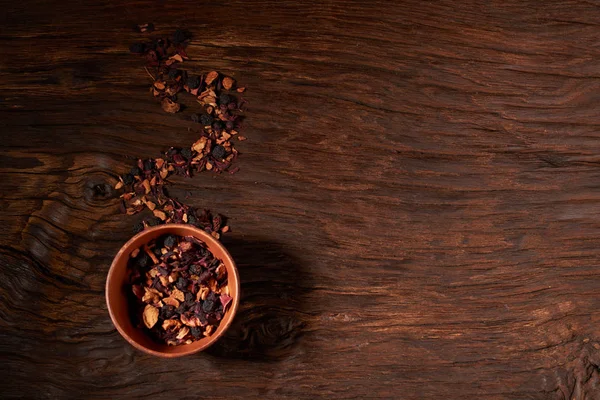 Kupası ve ahşap bir masaya izole kuru çay yaprakları