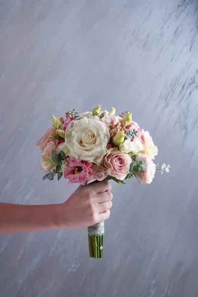 Woman hand hold wedding bouquet on gray background