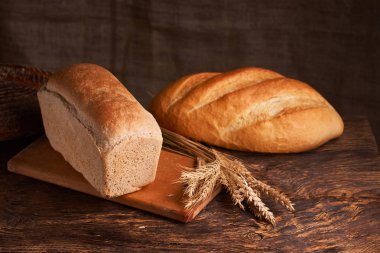 Fırın ekmek üreticileri - altın rustik huysuz somun ekmek ve siyah kara tahta zemin üzerine buns