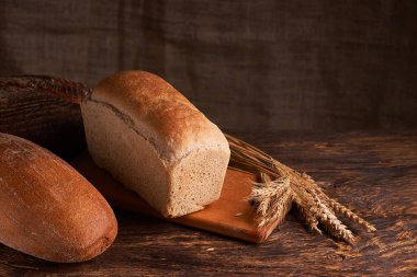 Fırın ekmek üreticileri - altın rustik huysuz somun ekmek ve siyah kara tahta zemin üzerine buns
