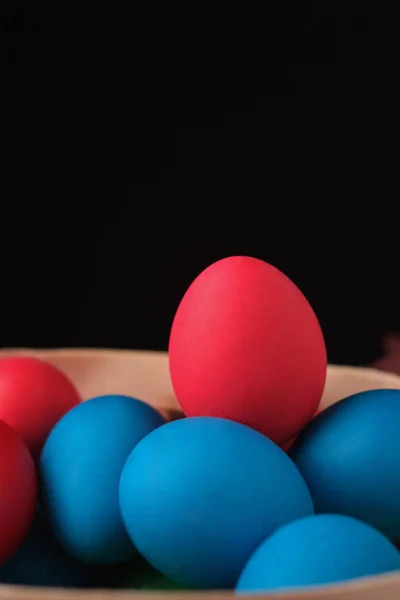 Colored easter eggs on black background. Red egg on top on blue eggs