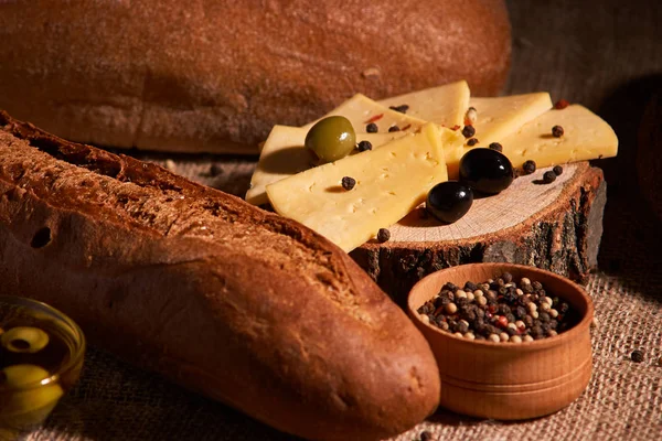 Rebanadas de queso en el escritorio de madera entre diferentes panes. lugar para el texto — Foto de Stock