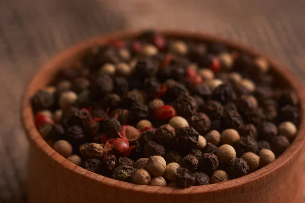 Peppercorns en un tazón de madera en la mesa con comida de estilo rústico. Comida casera —  Fotos de Stock