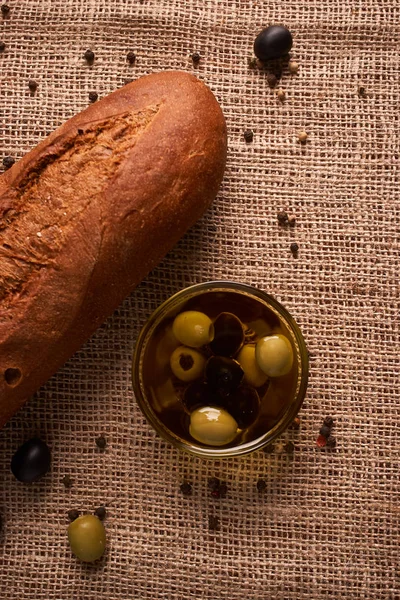 Baguette de pan fresco con aceite de oliva, aceitunas. queso y romero sobre fondo de madera. Desayuno teasty — Foto de Stock