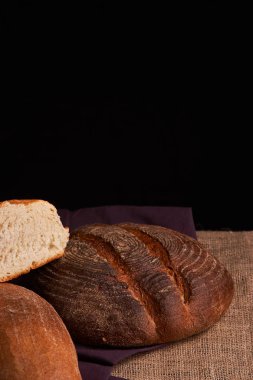 Fırın ekmek üreticileri - altın rustik huysuz somun ekmek ve siyah kara tahta zemin üzerine buns. Natürmort yukarıdan yakalanan