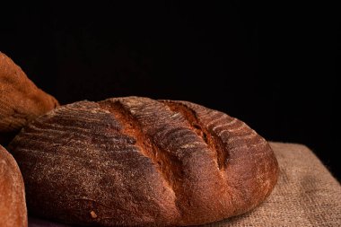 Fırın ekmek üreticileri - altın rustik huysuz somun ekmek ve siyah kara tahta zemin üzerine buns. Natürmort yukarıdan yakalanan