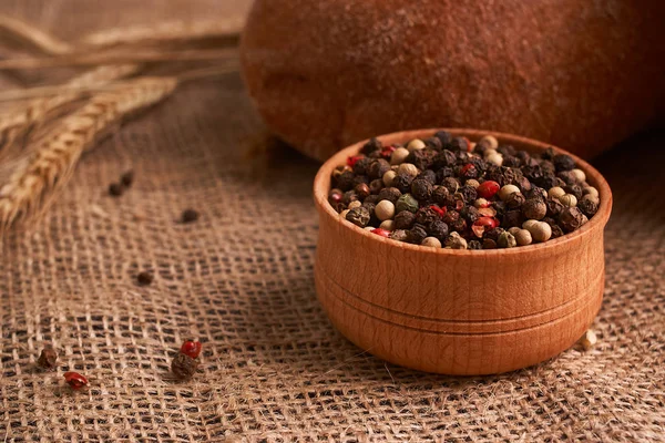 Peppercorns en un tazón de madera en la mesa con comida de estilo rústico. Comida casera —  Fotos de Stock