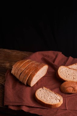 koyu ahşap masa ve kahverengi peçete üzerinde ekmek. Ekmek dilimleri ve kırıntıları yukarıdan izlendi. Üstten Görünüm