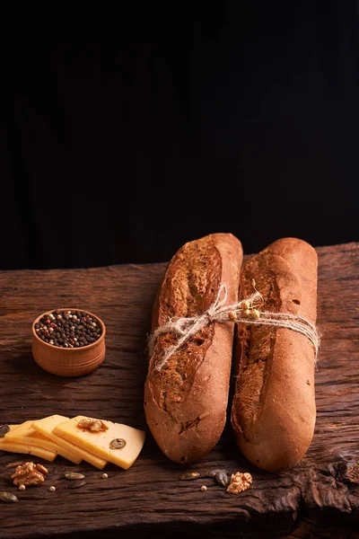 Ekmek ve iki baget ekmek yığını ile masada ahşap bir kaseye karabiber. Ev yapımı yiyecek