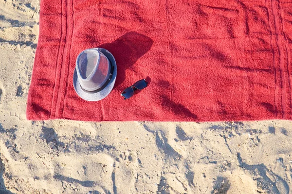 Červená Froté ručník na světlém pozadí s klobouk a sluneční brýle, pohled shora — Stock fotografie