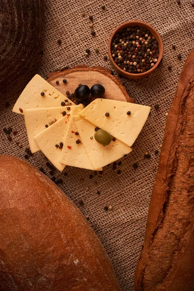 Rebanadas de queso en el escritorio de madera entre diferentes panes. lugar para el texto — Foto de Stock