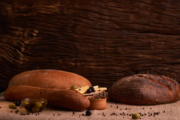 Panadería - pan crujiente rústico de oro y bollos sobre fondo de pizarra negro. Bodegón capturado desde arriba — Foto de Stock