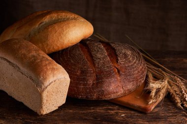 Fırın ekmek üreticileri - altın rustik huysuz somun ekmek ve siyah kara tahta zemin üzerine buns. Natürmort yukarıdan yakalanan