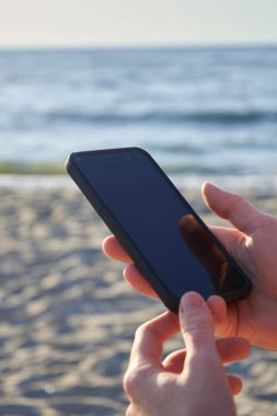 Sevimli gülümseyen kız manifatura bir plajda cep telefonu mesajı ile. Nice sakin ol