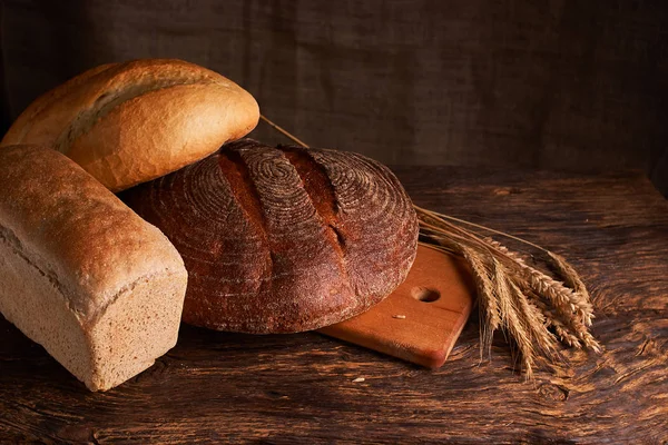 Versgebakken brood op donkere houten keukentafel. Selectieve aandacht — Stockfoto