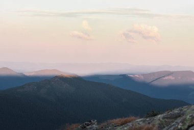 Güneşli bir günde dağlar ve bulutlar ve iğne yapraklı orman ile gün batımı. Manzara