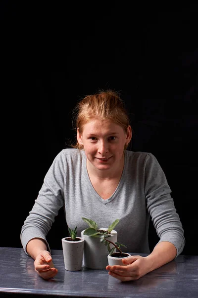 Une belle femme montre de l'amour à ses plantes dans des pots en béton — Photo