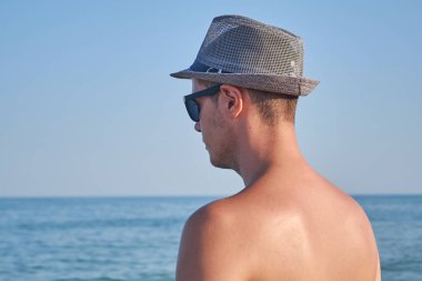 Kendine güvenen ve yakışıklı. Yakışıklı genç adam deniz manzara, güzel güneşli bir günde rahat adam bakmak