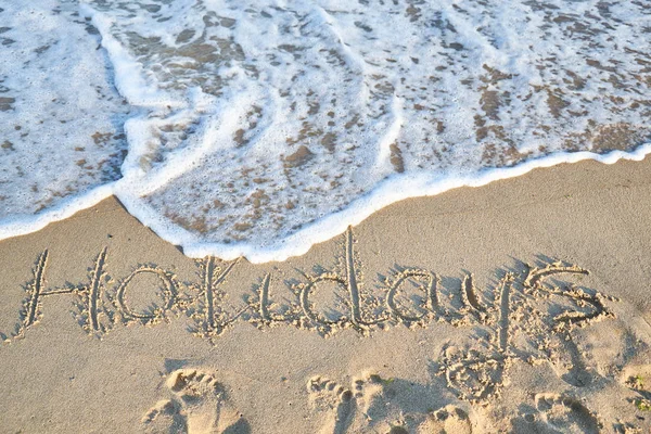 Holiday word is written on the beach sand — Stock Photo, Image