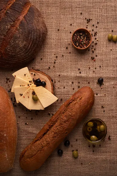 Traditional Dutch semi hard cheese served with olives on rural table with sacking. With baguette and bread — Stock Photo, Image