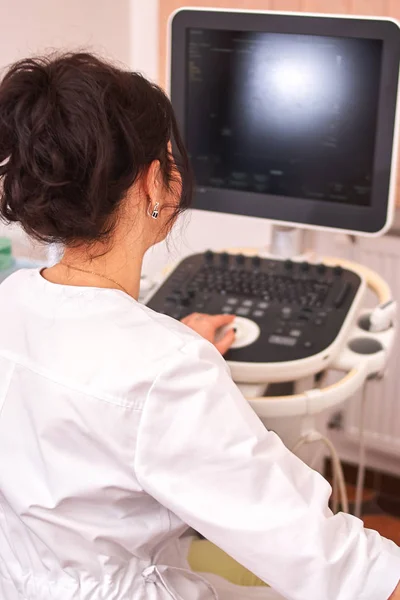 Olgun doktor hastanın ultrason teşhisini yapıyor. Ekrana bakarak beyaz tek giyen doktor