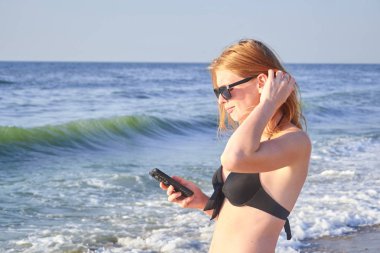 Sahilde bir cep telefonu tutan bir kadının elleri mockup görüntüsü. Seçici odak