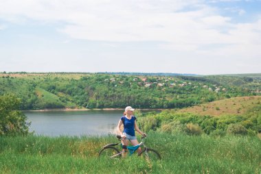 Nehir kıyısında bisiklet olan kız. Bir kız bisikletle bir çadırın yanında bisikletle oturur. Seyahat ve Özgürlük kavramı.