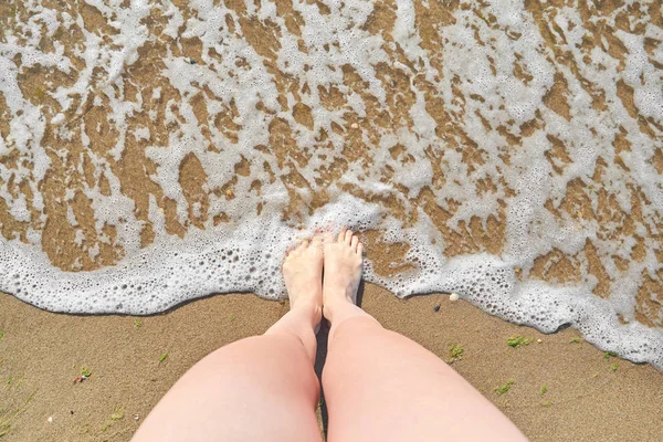 De pie en la playa con la ola del océano cubrir la pierna mirando desde arriba — Foto de Stock