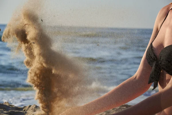 Όμορφη γυναίκα κάθεται στην παραλία πληκτρολογώντας άμμο στα χέρια της σε φόντο στη θάλασσα — Φωτογραφία Αρχείου