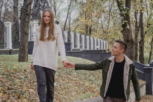 Verliebte Paare stehen auf herbstlichem Laub in einem Park und genießen einen schönen Herbsttag. Mann umarmt Mädchen — Stockfoto