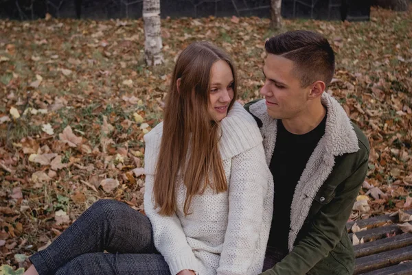 Ζευγάρι στην αγάπη στέκονται στο φθινόπωρο πεσμένα φύλλα σε ένα πάρκο, απολαμβάνοντας μια όμορφη φθινοπωρινή μέρα. Άντρας αγκαλιάζει κορίτσι — Φωτογραφία Αρχείου