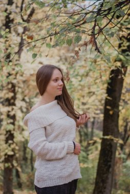 Renkli sonbahar yaprakları yakın beyaz kazak güzel bir kız portresi yakın. Romantik bir kadının eseri. Pretty hassasiyet modeli gülümseyen