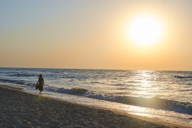 gün doğumu ve plaj. Yürüyen kişinin silueti. sakin deniz