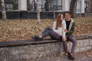 Parkta bir sonbahar gününde yürüyüş mutlu genç çift. Birlikte eğleniyorlar. Sevimli Genç