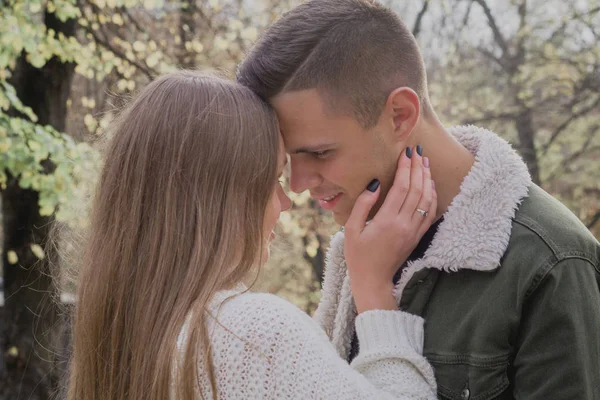 Pareja enamorada de pie sobre las hojas caídas de otoño en un parque, disfrutando de un hermoso día de otoño. Chica y niño en el perfil — Foto de Stock