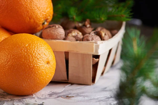Leckeres und gesundes Neujahrsfrühstück. Nüsse auf dem Holzkorb und Orangen auf weißem Hintergrund — Stockfoto