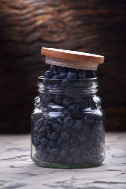 Yaban mersini taze ön görünüm eski beyaz rustik ahşap masa üzerinde cam kavanozda düzenleme yakın