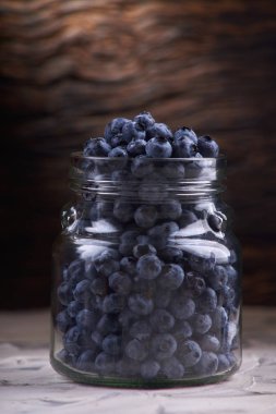 Yaban mersini taze ön görünüm eski beyaz rustik ahşap masa üzerinde cam kavanozda düzenleme yakın