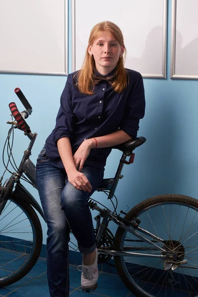 Portrait de jeune femme à vélo sur fond de mur bleu — Photo