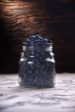 Yaban mersini taze ön görünüm eski beyaz rustik ahşap masa üzerinde cam kavanozda düzenleme yakın