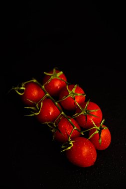 Dal üzerinde domatesler, siyah arkaplan