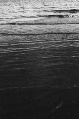 Su dokusuna yakın çekim, kıyıdaki pürüzsüz su dalgaları, suyun manzara fotoğrafı. 